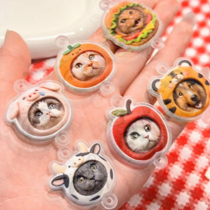 Five small animal figurines in clear plastic cases held in a hand with a red and white checkered background.