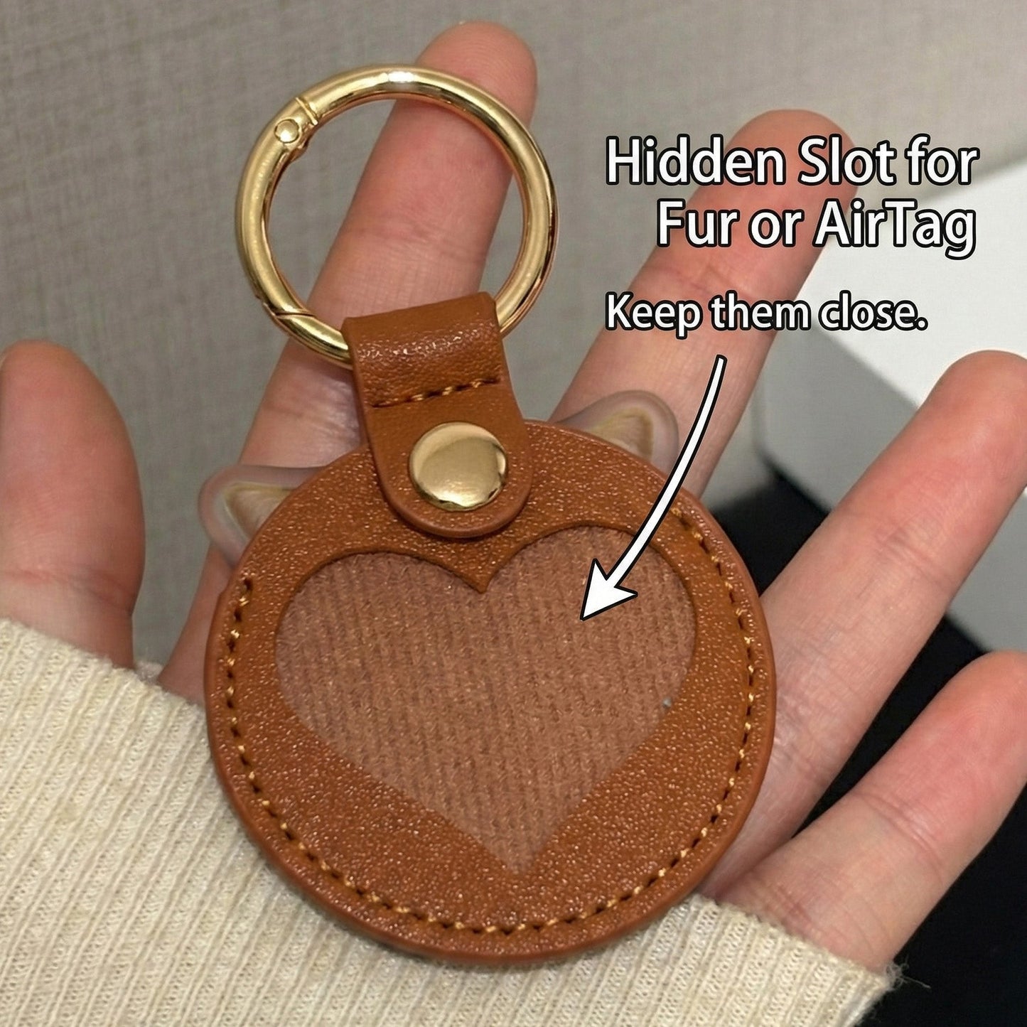 Brown leather keychain with heart design held by a hand, labeled for fur or AirTag attachment.
