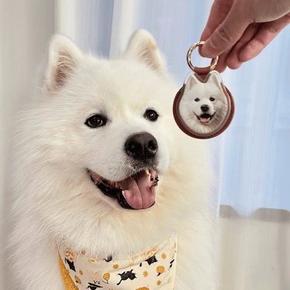 White dog wearing a bandana with a keychain featuring another dog's face.